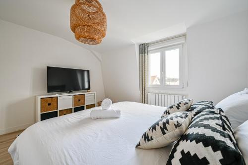 um quarto branco com uma televisão e uma cama em La Casa Blanca - 6 personnes proche Disney & Paris em Le Raincy