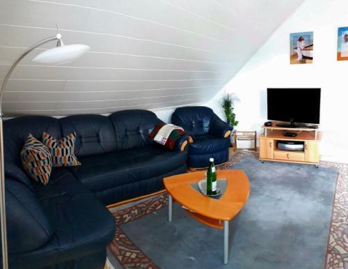 uma sala de estar com um sofá azul e uma mesa em Ferienwohnung Maria Miller em Hemfurth-Edersee