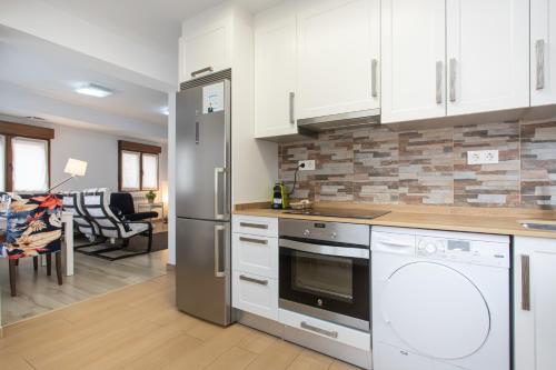 a kitchen with white cabinets and appliances and a living room at La Plaza de Cangas Apartamento Turistico in Cangas de Onís