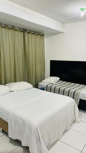 two beds in a hotel room with green curtains at Suite Proximo a Praia in Arraial do Cabo