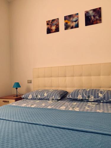 ヴェローナにあるDom a Veronaのベッドルーム1室(青いシーツと壁に絵画が飾られたベッド1台付)