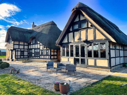 a thatched house with a table and chairs in front at Guest House gem in Wickhamford, near Broadway in Badsey