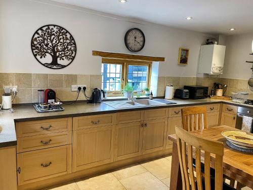 a kitchen with a sink and a clock on the wall at Guest House gem in Wickhamford, near Broadway in Badsey