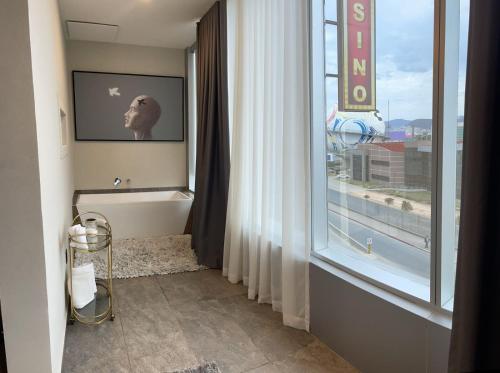 ein Bad mit einer Badewanne und einem großen Fenster in der Unterkunft Hotel Casino Grand Vía Dorada in Pachuca de Soto