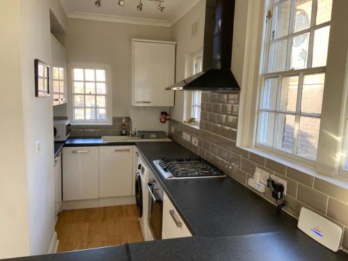 a kitchen with white cabinets and a stove top oven at Period Apartment On South Bank in London
