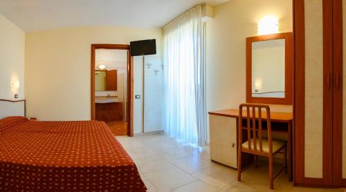 a bedroom with a bed and a desk and a mirror at Hotel Harmony in Rimini