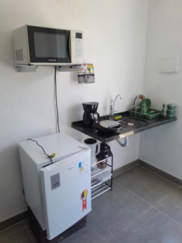 eine kleine Küche mit einem weißen Kühlschrank und einer Mikrowelle in der Unterkunft Suíte completa s/ Fogão in São Pedro da Aldeia