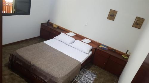 a bedroom with a bed with a wooden headboard at Quarto Quádruplo in São Pedro