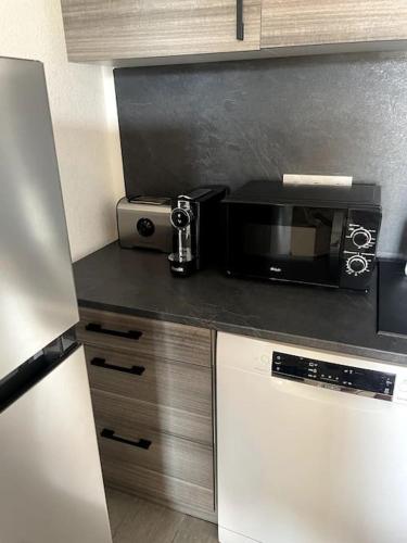 une cuisine avec un comptoir noir avec un micro-ondes dans l'établissement Très beau T2 idéalement situé., à Bastia