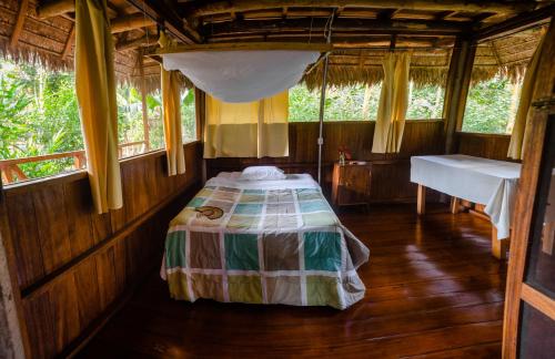 1 dormitorio con 1 cama en una habitación con ventanas en Tres Chimbadas Lake Lodge en Tambopata