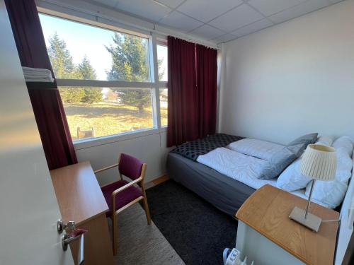 um quarto com uma cama, uma secretária e uma janela em Godaland Guesthouse em Hlíðarendi
