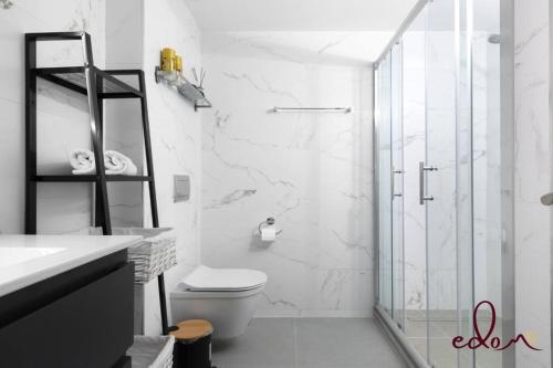 a white bathroom with a shower and a toilet at סוויטה משפחתית מרווחת עם נוף לים - By Edomlux in Eilat