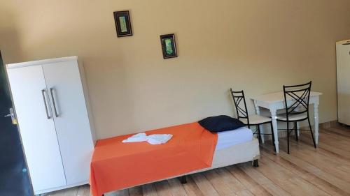 1 dormitorio con 1 cama, mesa y sillas en Pousada Apucarana - Sede en Apucarana