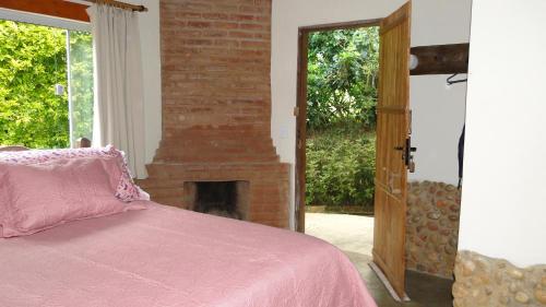 a bedroom with a fireplace and a bed with a pink blanket at Pousada Pé da Mata in Aiuruoca