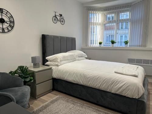 a bedroom with a bed and a chair and a clock at Studio Flat in Luton Town Centre in Luton
