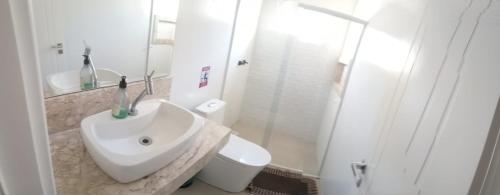 Suíte Deluxe في إيتاجاي: حمام أبيض مع حوض ومرحاض