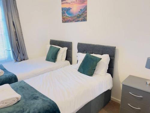 a bedroom with two beds with green and white pillows at Starview Apartment-Vitoria in Lexden