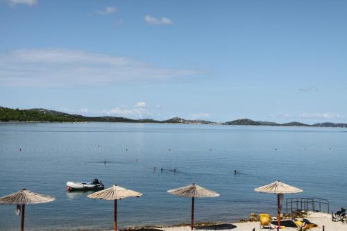 einen Strand mit Sonnenschirmen und einem Boot im Wasser in der Unterkunft Apartments Lord Pirovac in Pirovac