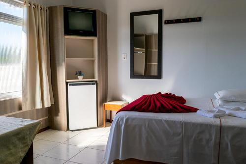 a bedroom with a bed with a red blanket on it at HOTEL TAIÓ in Taió