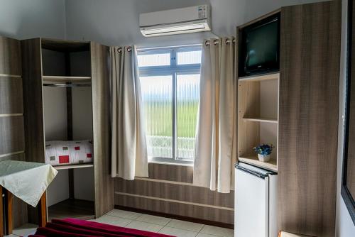 een kleine kamer met een raam en een televisie bij HOTEL TAIÓ in Taió