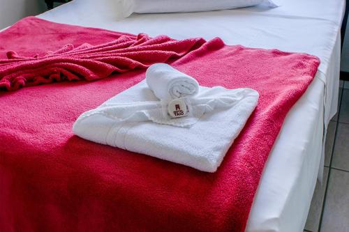 een witte handdoek op een bed met een rode deken bij HOTEL TAIÓ in Taió