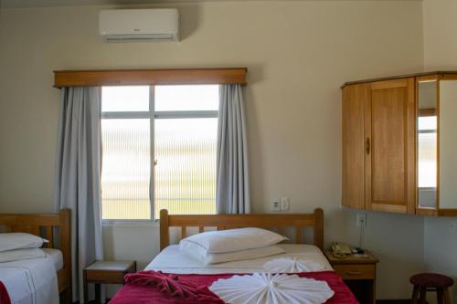 a small bedroom with two beds and a window at HOTEL TAIÓ in Taió