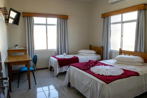 a room with two beds and a desk and windows at HOTEL TAIÓ in Taió
