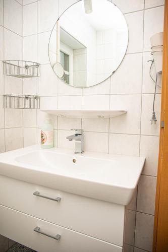 a white bathroom with a sink and a mirror at Ferienwohnungen Saida Wohnung 2 in Norden