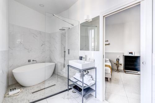 a white bathroom with a tub and a sink at Le Angioine Rooms in Naples