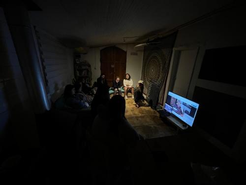a group of people sitting in a dark room with a television at SURFHOUSE Pichilemu in Pichilemu