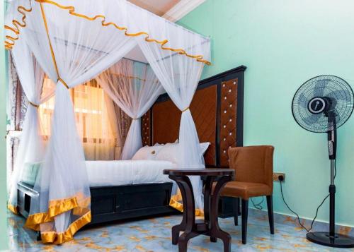 1 dormitorio con 1 cama con ventilador y silla en Romeos Hotel Luzira Kampala, en Kampala