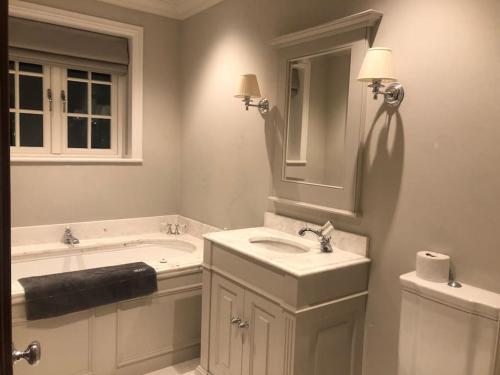 a bathroom with a sink and a tub and a mirror at Islandon House The Jurassic Coast in Hamworthy