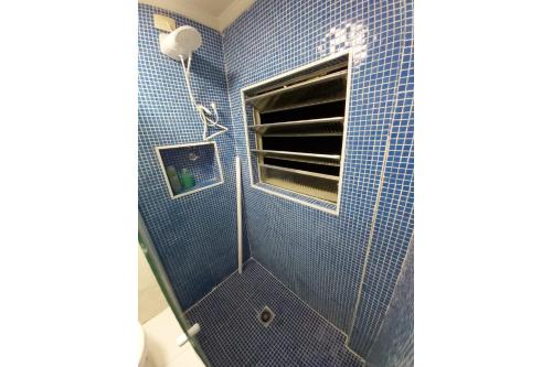 um chuveiro de azulejos azuis com uma janela na casa de banho em CONDOMÍNIO BANDEIRANTES em São Paulo