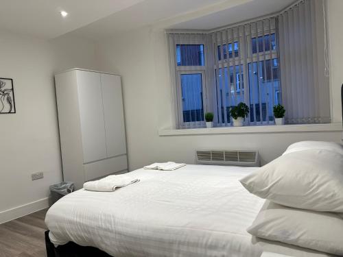 a bedroom with a large white bed with two windows at Modern Apartment in Luton town Centre in Luton