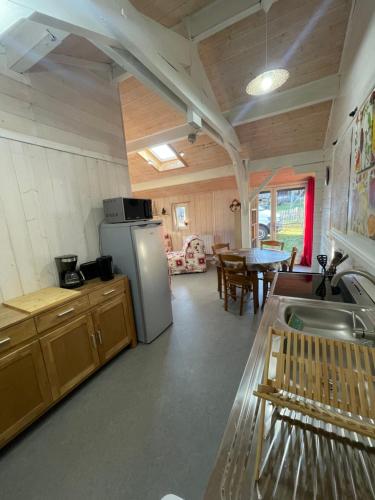 a kitchen and dining room with a refrigerator and a table at Les Cachettes du Hérisson - Le Hérissonneau in Le Frasnois