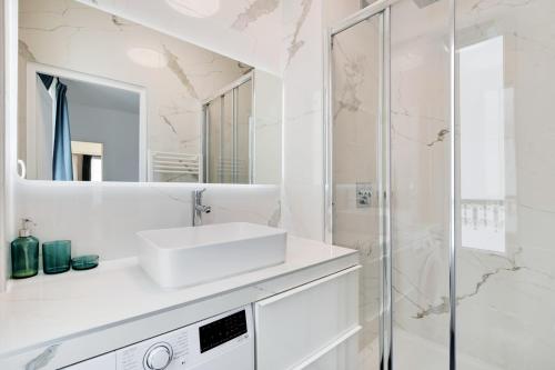 une salle de bain blanche avec un lavabo et une douche dans l'établissement Appartement spacieux -1BDR/4P -Le bas Montmartre, à Paris