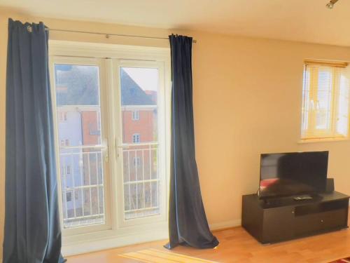 een woonkamer met blauwe gordijnen en een televisie bij Starview Apartment 101 in Colchester