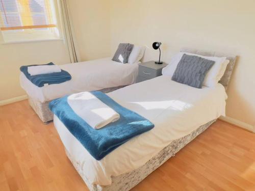 two beds with a blue blanket on them in a room at Starview Apartment 101 in Colchester
