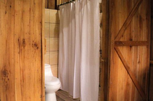 a bathroom with a toilet and a shower curtain at Finca La Unión in Turrialba