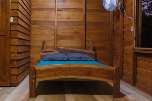 Cama pequeña en habitación con paredes de madera en Finca La Unión en Turrialba