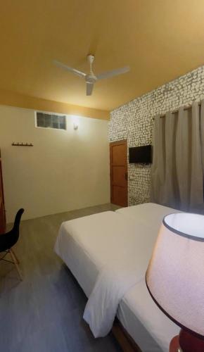 a bedroom with a large white bed and a fan at Sandy Heaven Maldives in Gulhi