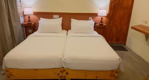 a bedroom with two beds with white sheets and two lamps at Sandy Heaven Maldives in Gulhi