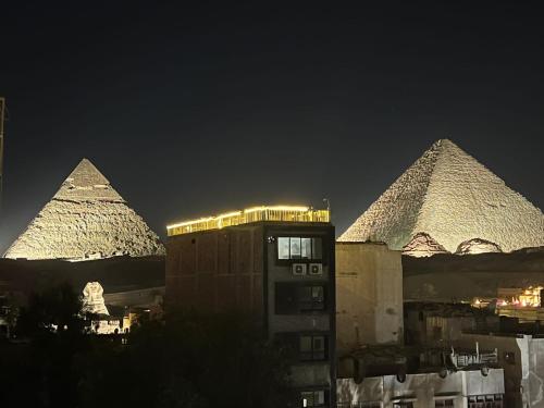 a group of pyramids are lit up at night at Prince Pyramids Inn in Cairo