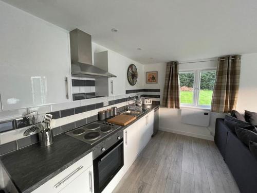 a kitchen with white cabinets and a black counter top at Gorgeous modern furnished cabin in Steyning in Steyning