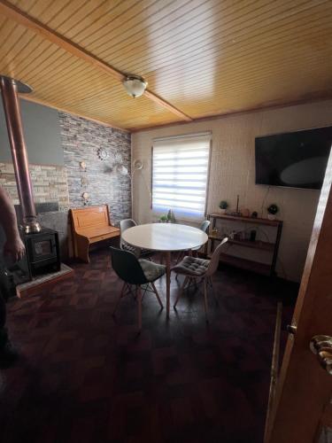 Habitación con mesa, sillas y chimenea. en Casa capdeville, en Puerto Williams