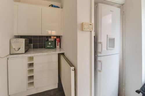  La cuisine est équipée de placards blancs et d'un réfrigérateur. dans l'établissement K50 Luxury Lodge Darren House, à Middleton
