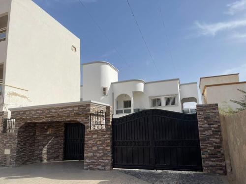 a white house with a black gate and a fence at La cave aux variétés in Nouakchott