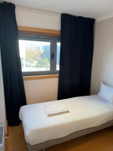 a bedroom with a bed and a window with black curtains at Expo 53 in Lisbon