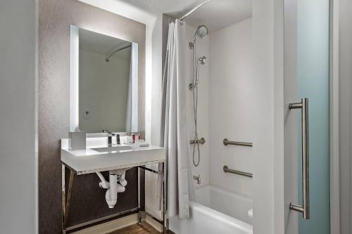 La salle de bains blanche est pourvue d'un lavabo et d'une douche. dans l'établissement Marriott Orlando Downtown, à Orlando
