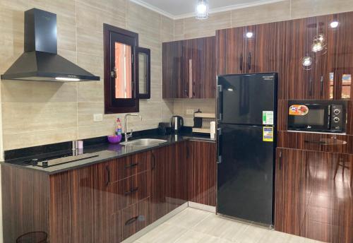 a kitchen with wooden cabinets and a black refrigerator at Elite Apartment in Sharm El Sheikh